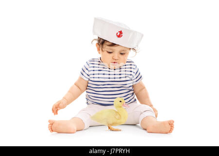 Babymädchen in einem Seemann-Outfit mit einer kleinen Entlein vor ihr isoliert auf weißem Hintergrund Stockfoto