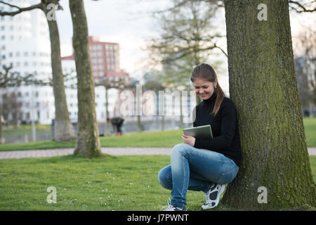 junge Frau im schwarzen Pullover mit Tablet-pc im park Stockfoto