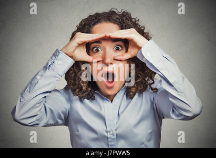 Closeup Portrait, betäubt Kopfschuss junge neugierige Frau, guckend aussehende wie Fernglas suchen etwas Zukunft prognostizierte isoliert g durch Finger Stockfoto