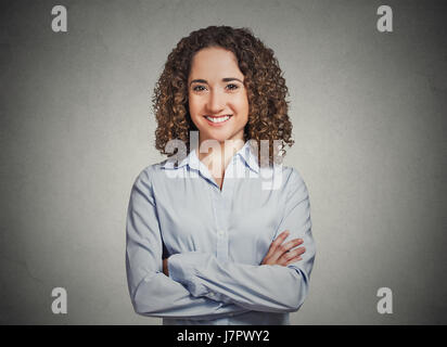 Closeup Portrait, glückliche, selbstbewusste, erfolgreiche junge berufstätige Frau in blauem Hemd mit Armen gekreuzt gefalteten isolierte graue Wand Hintergrund. Positive Stockfoto