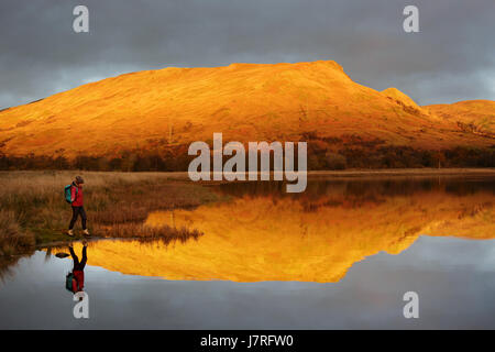 Frau zu Fuß am See vor einem Berg, Schottland, UK. Stockfoto