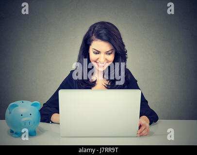 Happy Geschäftsfrau arbeiten mit Laptop am Schreibtisch sitzen und das Sparschwein Stockfoto