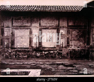 Dieses Foto von Giacomo Brogi zeigt die Wand des Augustustempels in Pompeji, auch als Pantheon bezeichnet. Das Bild zeigt die Ruinen dieses antiken römischen Tempels und betont seine architektonische und historische Bedeutung im Kontext der archäologischen Stätte Pompeji. Stockfoto