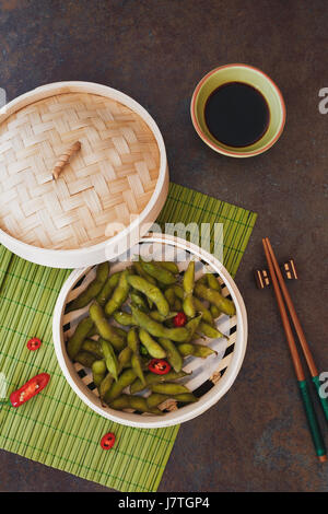 Edamame Sojabohnen mit Salz in Bambus Dampfgarer warm serviert. Ansicht von oben, Leerzeichen Stockfoto