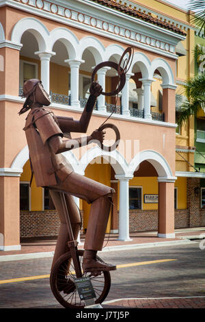 Jongleur auf einem Einrad - eine Metallskulptur von Edgardo Carmona auf einem Display des Gehwegs auf First Street, Fort Myers, Florida, USA Stockfoto