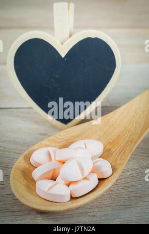 Rosa Pillen in Holzlöffel mit leeren Herzen Form blackboard Stockfoto