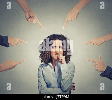 Auf grauen Büro Wand Hintergrund isoliert Konzept der sozialen Anklage schuldig Geschäftsfrau viele Finger zu zeigen. Porträt Angst ängstlich verlegen Stockfoto