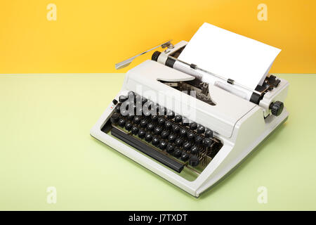 Vintage-Objekte - Retro Schreibmaschine auf einem gelben Hintergrund und einen grünen Tisch. Stockfoto
