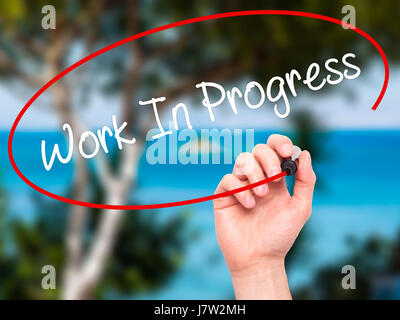 Hand des Mannes Work In Progress mit schwarzem Filzstift auf Bildschirm zu schreiben. Isoliert auf Natur. Wirtschaft, Technologie, Internet-Konzept. Stock Foto Stockfoto