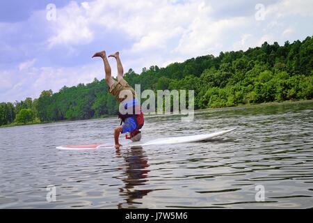 Mann steht auf dem Kopf auf einem paddleboard Stockfoto