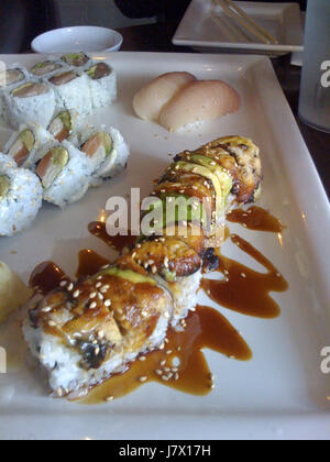 Dieses Bild stellt eine Sushi-Platte dar, die eine Auswahl frisch zubereiteter Sushi-Gerichte zeigt. Es beleuchtet die Handwerkskunst der Sushi-Herstellung und die kulinarische Kultur hinter diesem beliebten japanischen Gericht. Stockfoto