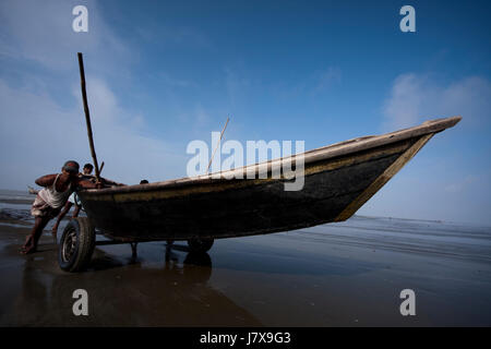 Fischer schieben ein Boot am Strand Kuakata Meer. Patuakhali, Bangladesch. Stockfoto