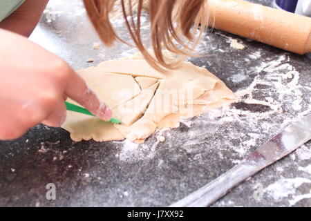 Eines Kindes Hände sorgfältig Schnittformen in Plätzchenteig Stockfoto