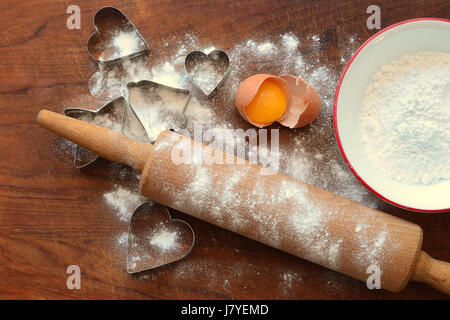 Rollende Holz mit Backen, Zutaten, Mehl, Eiern, Ausstechformen auf Holzbrett Stockfoto