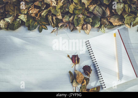 Draufsicht auf Notebook und trocken rose Blume auf weiße Holzterrasse mit dem leeren Raum für Design. Für Liebe oder Valentine Tag-Konzept Stockfoto