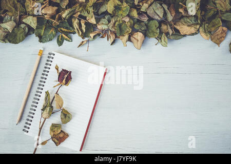 Draufsicht auf Notebook und trocken rose Blume auf weiße Holzterrasse mit dem leeren Raum für Design. Für Liebe oder Valentine Tag-Konzept Stockfoto