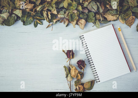 Draufsicht auf Notebook und trocken rose Blume auf weiße Holzterrasse mit dem leeren Raum für Design. Für Liebe oder Valentine Tag-Konzept Stockfoto