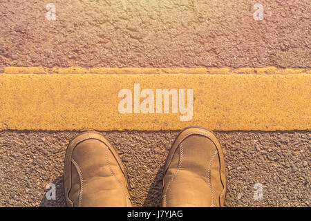 Nahaufnahme neue Männer Modeschuhe auf Asphaltstraße neben gelben Streifen Stockfoto