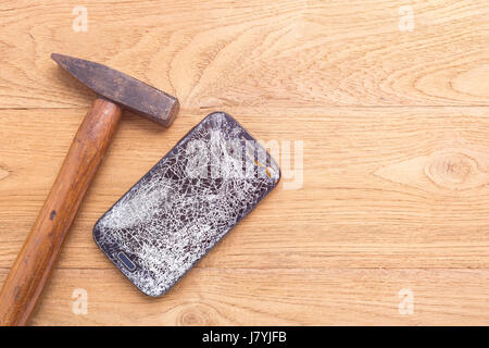 Oben gebrochen Schwarz Smartphone anzeigen und hammer auf Holztisch Hintergrund Stockfoto