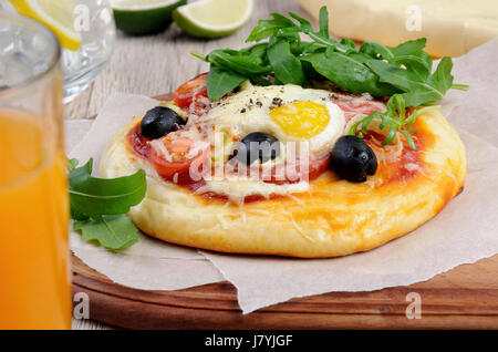 Mini Pizza mit Würstchen und Ei und Rucola für Frühstück Stockfoto