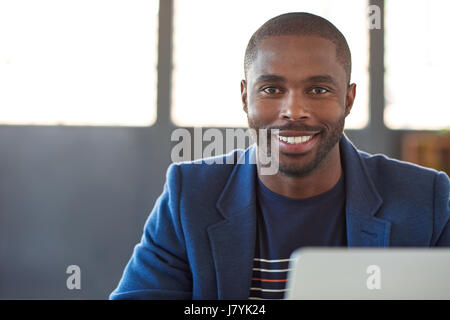 Lächelnde afrikanische Geschäftsmann auf einem Laptop in einem Büro arbeiten Stockfoto