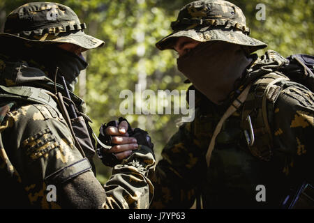 Zwei Soldaten Händeschütteln in Wäldern bei Tag Stockfoto
