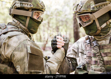 Zwei Soldaten Händeschütteln in Wäldern bei Tag Stockfoto