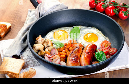 Englisches Frühstück mit Spiegelei, Würstchen, Speck, Bohnen, Toast, Tomaten und Pilze. Stockfoto