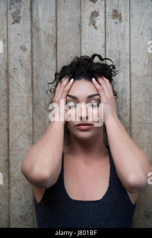 Junge Frau auf dem Boden Kopf in Händen mit Kopfschmerzen Schmerzen Festlegung betonte Stockfoto