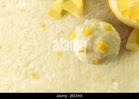 Ice Cream Geschmack Zitrone Textur Hintergrund mit Ball. Garniert mit Zitrone Stücke Obst. Ansicht von oben. Horizontale Komposition. Stockfoto