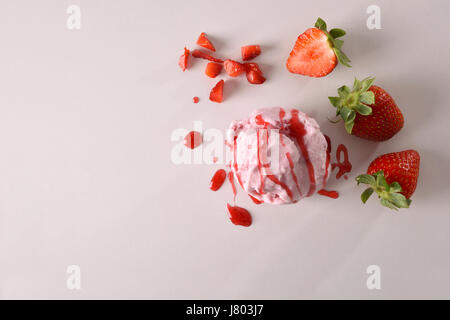 Eis Erdbeer Textur Hintergrund mit Kugel isoliert auf weißen Tisch gewürzt. Garniert mit Erdbeer Stücke Obst und Sirup. Ansicht von oben. Horizo Stockfoto