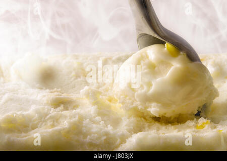 Zitrone-Eis-Kugel hautnah zu machen. Vorne erhöhten Blick auf Eis Container und Schaufel Kommissionierung Produkt. Mit kaltem Dampf im Hintergrund. Vordere e Stockfoto