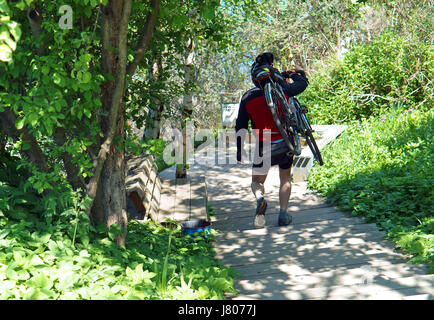 Der Radfahrer steigt auf der Treppe mit dem Fahrrad n apleche Stockfoto