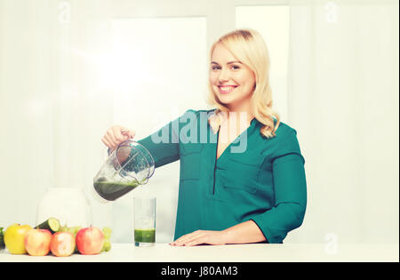 glückliche Frau mit Mixer Krug gießen Saft zu Hause Stockfoto