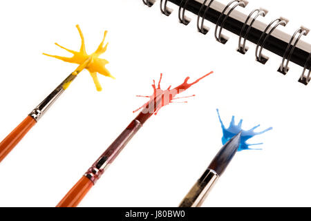 Nahaufnahme der Pinsel in Farbe und Spritzer auf dem Papier Stockfoto