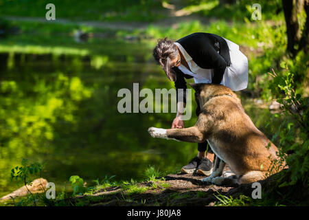 Die Frau verbringt Zeit mit American Akita Hund am Teich Stockfoto