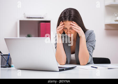 Junge Unternehmerin hat Kopfschmerzen bei der Arbeit. Stockfoto