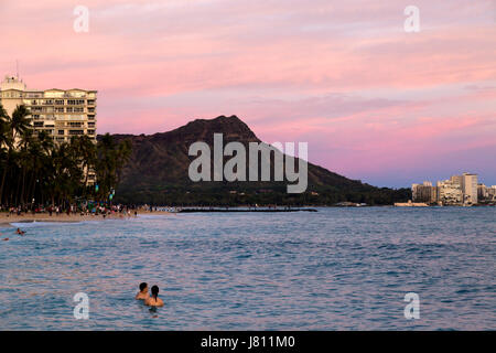 Bunter Blick bei Sonnenuntergang des Diamond Head auf Oahu, Hawaii. Junges Paar in den Ozean Szene betrachten. Stockfoto