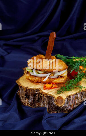 leckere Hähnchen-Sandwich mit Zwiebel Tomaten Gurke auf einem Holzständer-Tischplatte Stockfoto