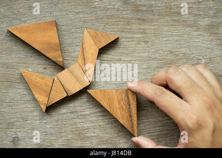 Mann halten Dreieck, Tangram-Puzzle in Vogel-Form zu erfüllen (Konzept für die Freiheit, frei leben oder entdecken Sie neue Welt) Stockfoto