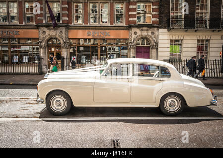 Ein weißer Rolls Royce Silver Cloud, auf dem Weg zu einer Hochzeit, vor dem Spink Auction House an der Southampton Row, London, England, Großbritannien Stockfoto