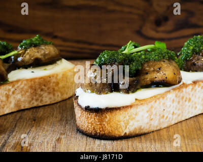 Bruschetta mit gebackenen Champignons, Frischkäse und Spinatsauce Stockfoto