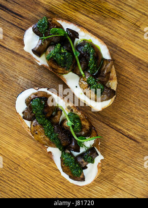 Bruschetta mit gebackenen Champignons, Frischkäse und Spinatsauce Stockfoto