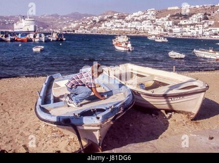 Chora, Mykonos, Griechenland. 3. Oktober 2004. Ein kleiner Junge spielt auf einem gestrandeten Boot in der geschäftigen, malerischen alten Hafen Chora. Mykonos zieht jedes Jahr viele Besucher und Tourismus ist ein wichtiger Wirtschaftszweig. Bildnachweis: Arnold Drapkin/ZUMA Draht/Alamy Live-Nachrichten Stockfoto