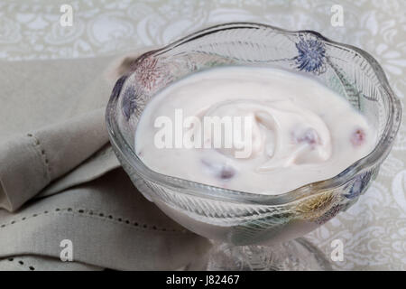 Griechischen Naturjoghurt mit Beeren gemischt in schönen Glas Darm mit Serviette - Essen Hintergrund mit cremigem Joghurt auf Löffel Stockfoto