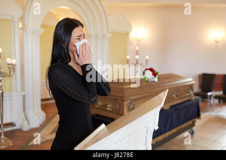 Frau, die weinend in der Nähe von Sarg bei Beerdigung in der Kirche Stockfoto