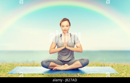 Frau macht Yoga Meditation in Lotus Pose auf Matte Stockfoto