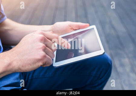 Lässige Person mit digitalen Tablettcomputer außerhalb mit w-LAN kommunizieren Stockfoto