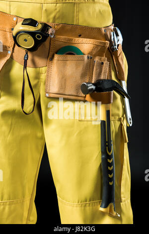Close-up Teilansicht des Arbeiters in Werkzeuggürtel auf schwarz Stockfoto