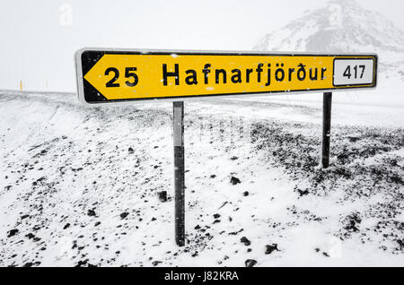 Gelben isländischen Straßenschild mit Ziel und Distanz steht am Straßenrand in kalten verschneiten Wintertag Stockfoto